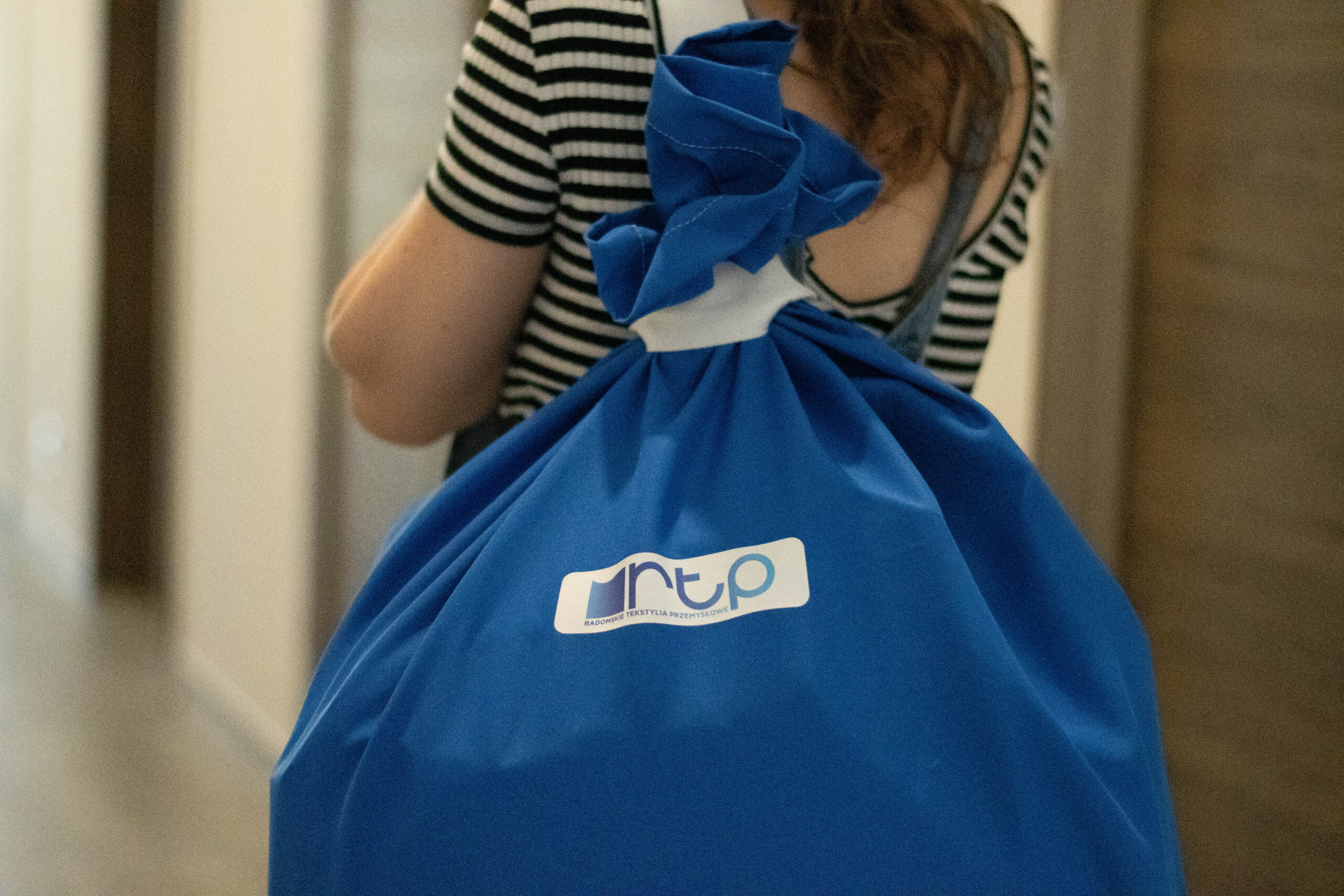 A blue laundry transport bag with the RTP Radom logo carried on the back by an employee.